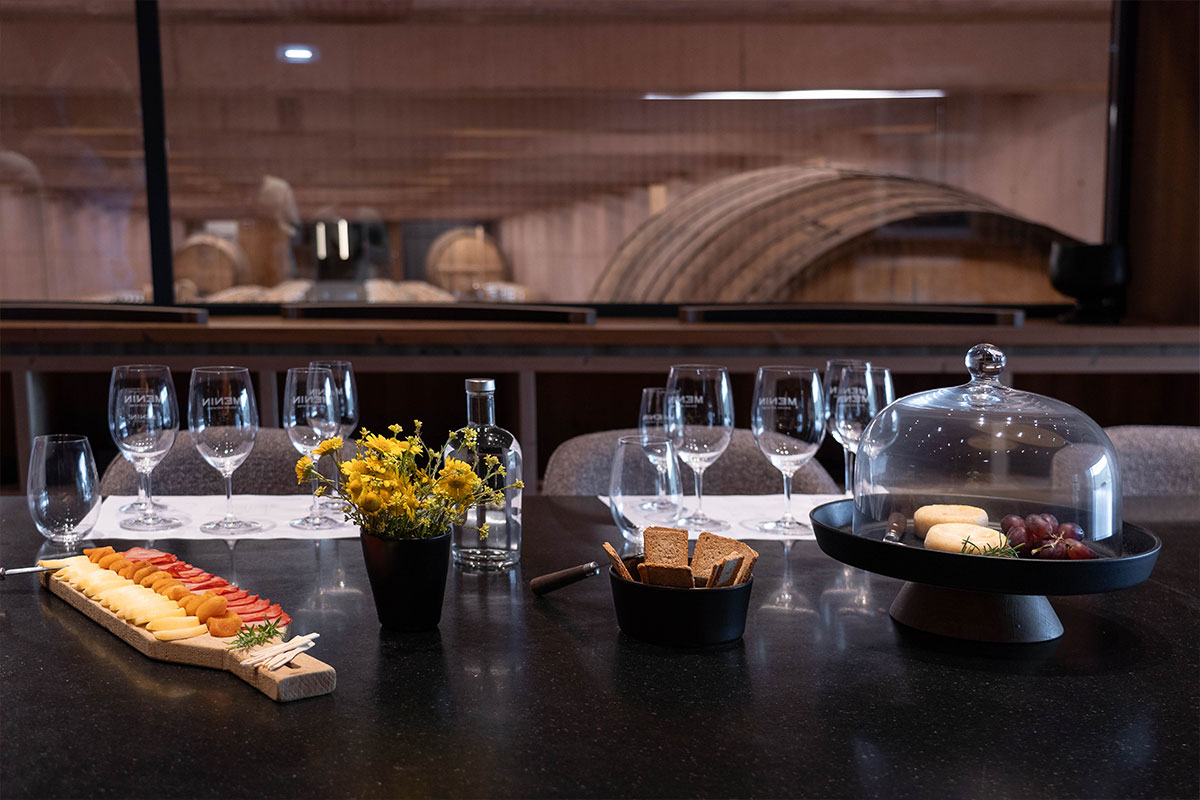 photograph of a table ready for a wine tasting, with the wine cellar in the background
